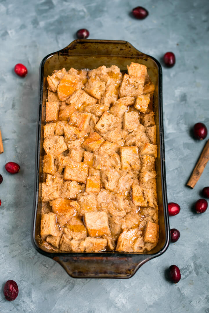 A baked vegan bread pudding in a loaf pan on a blue background