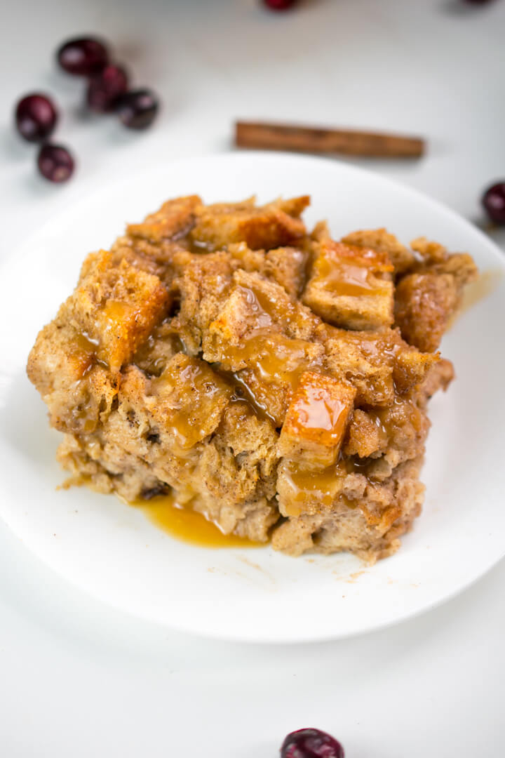 A serving of vegan bread pudding on a plate, drizzled with a golden brown sugar glaze.