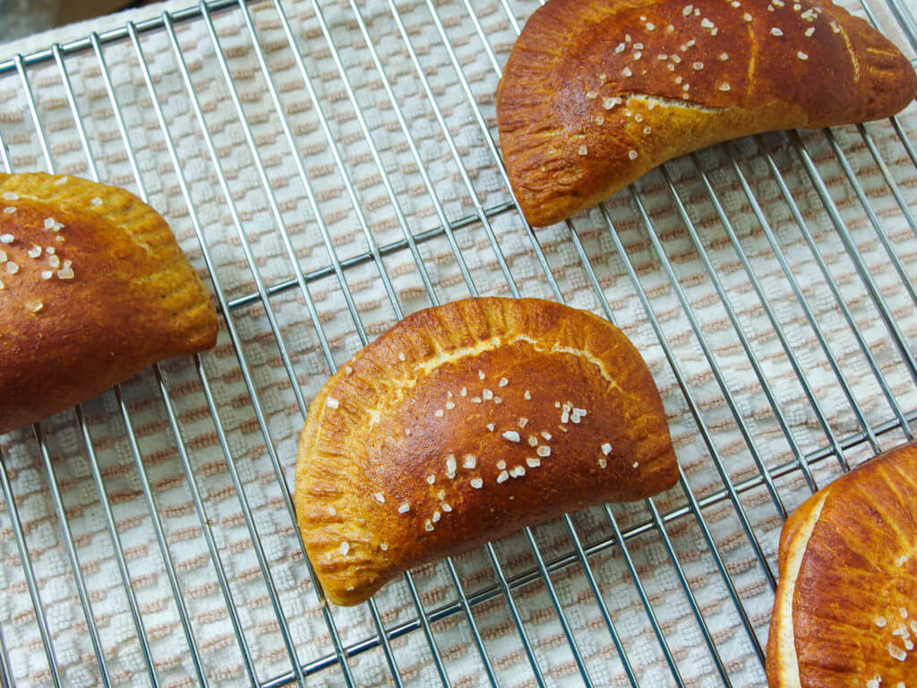 close up of baked pretzel empanadas with salt on cooling rack