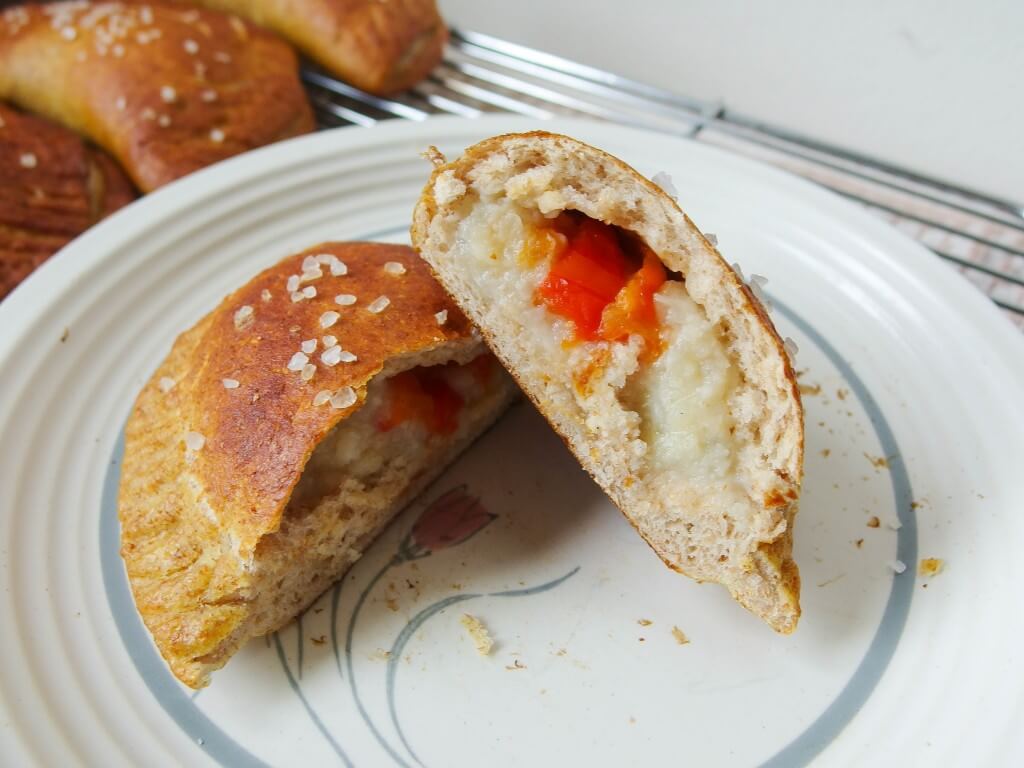 filling of a baked pretzel empanada made with pureed cauliflower, roasted garlic, and roasted red bell pepper on white plate