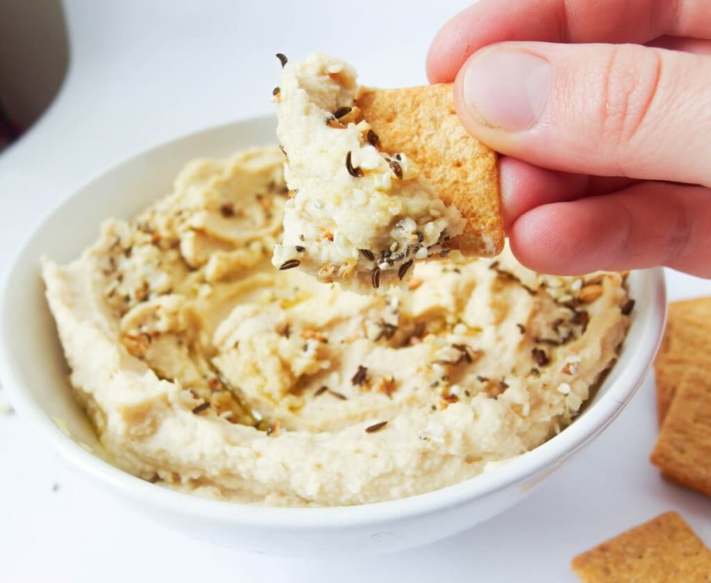 chip dipped in everything bagel hummus with spices