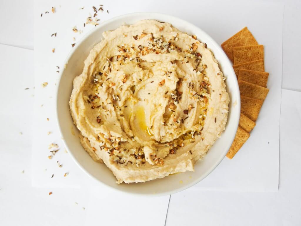 everything bagel hummus shot from above in a white bowl with crackers on the side