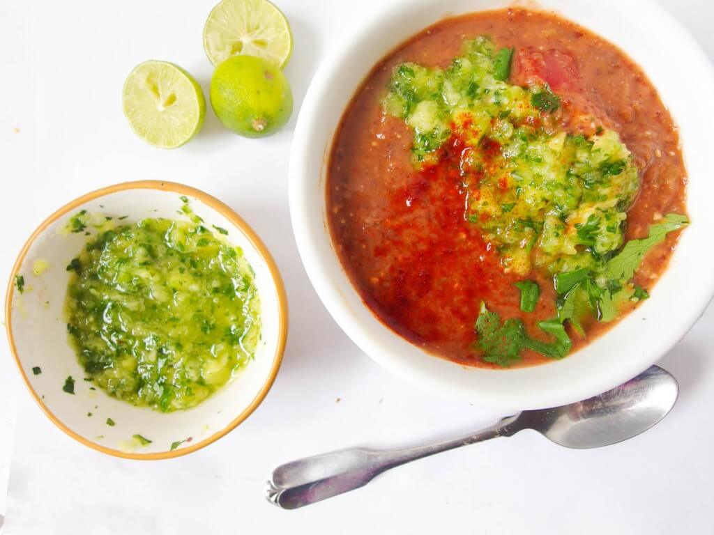close up of Chipotle Black Bean Soup with green pineapple salsa served with lime and a spoon