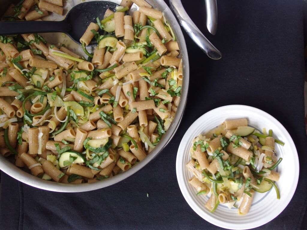 zucchini, garlic scape, and look pasta served on a white plate with entire pot