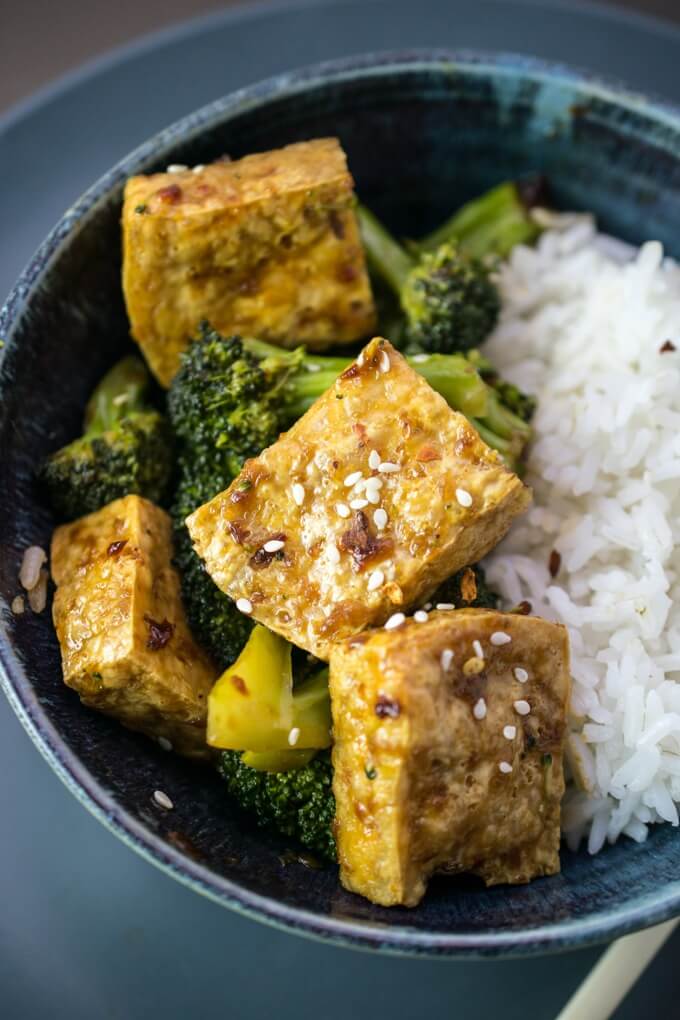 Crispy tofu bulgogi tossed in a Korean marinade with sesame seeds, served in a blue bowl with broccoli and white rice.