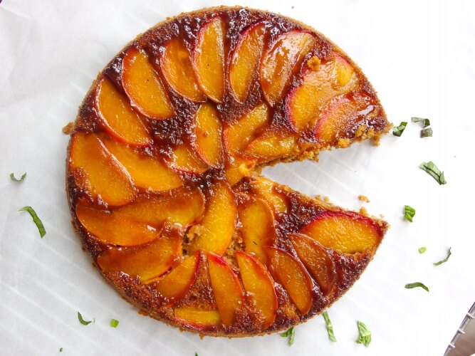 Fresh stone fruit upside down cake with slice missing cut out garnished with nutmeg, cinnamon, and ginger