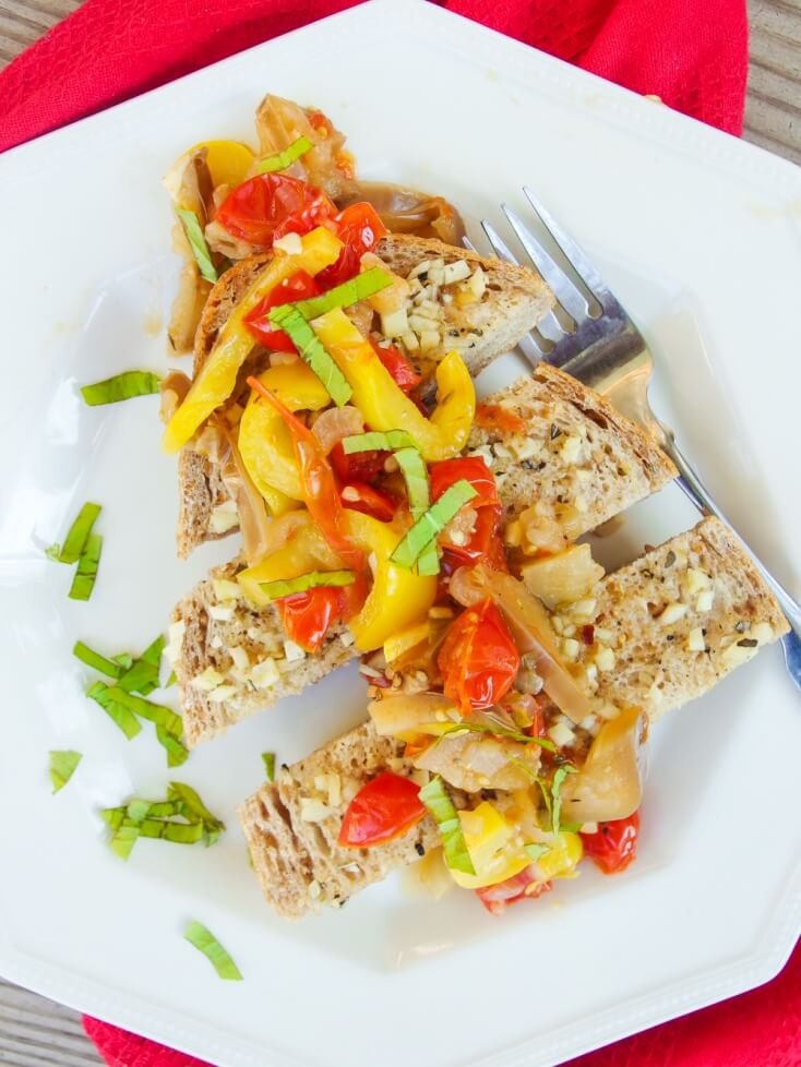 Gluten free and Vegan fresh summer vegetable Ratatouille served on crispy garlic bread on a white plate with a fork - Yup, it's Vegan