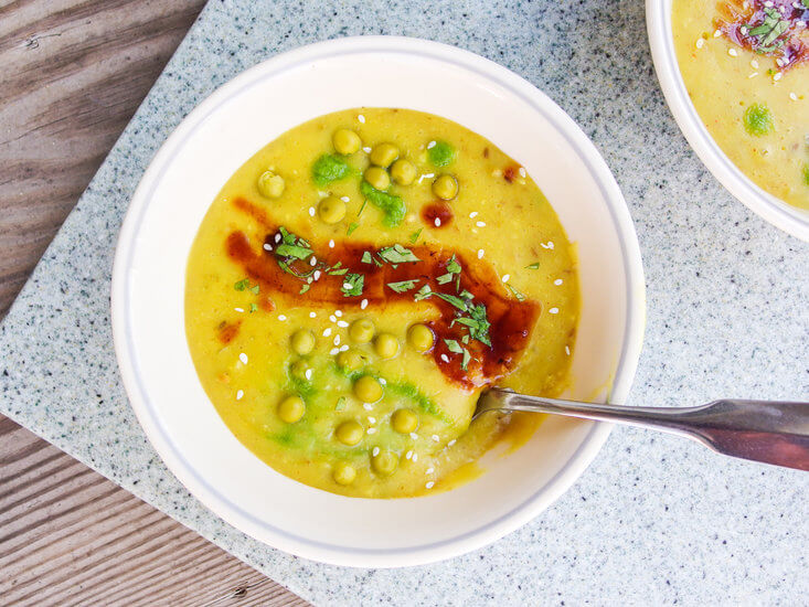 Closeup of hot and silky vegan Indian samosa soup with green peas, chickpeas, or mung beans and fresh cilantro - 