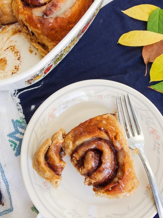 One plated and cut sweet and salty, rich pretzel cinnamon roll with a soft inside and a crunchy, browned outside served with a full pan of nine | yupitsvegan.com