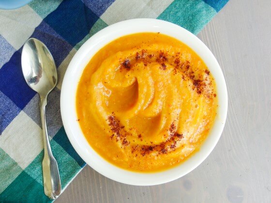 Close up of a bowl of oil free fall acorn squash soup topped with chili powder and a squeeze of lime. Simple and perfect for thanksgiving!