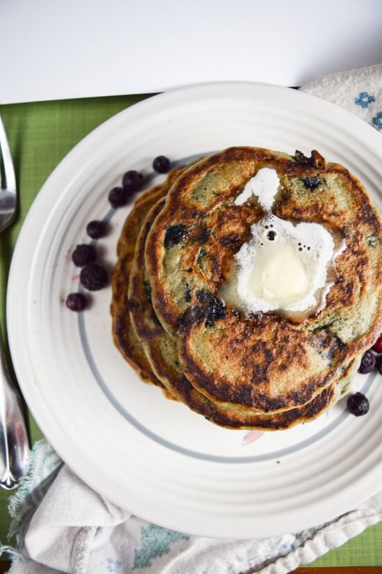A stack of warm and filling soft healthy blueberry pancakes served with chocolate chips and melted butter