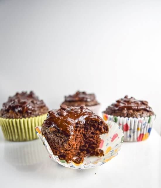 Four oil free healthy vegan avocado chocolate cupcakes frosted with a rich gooey peanut butter chocolate ganache and a bite taken
