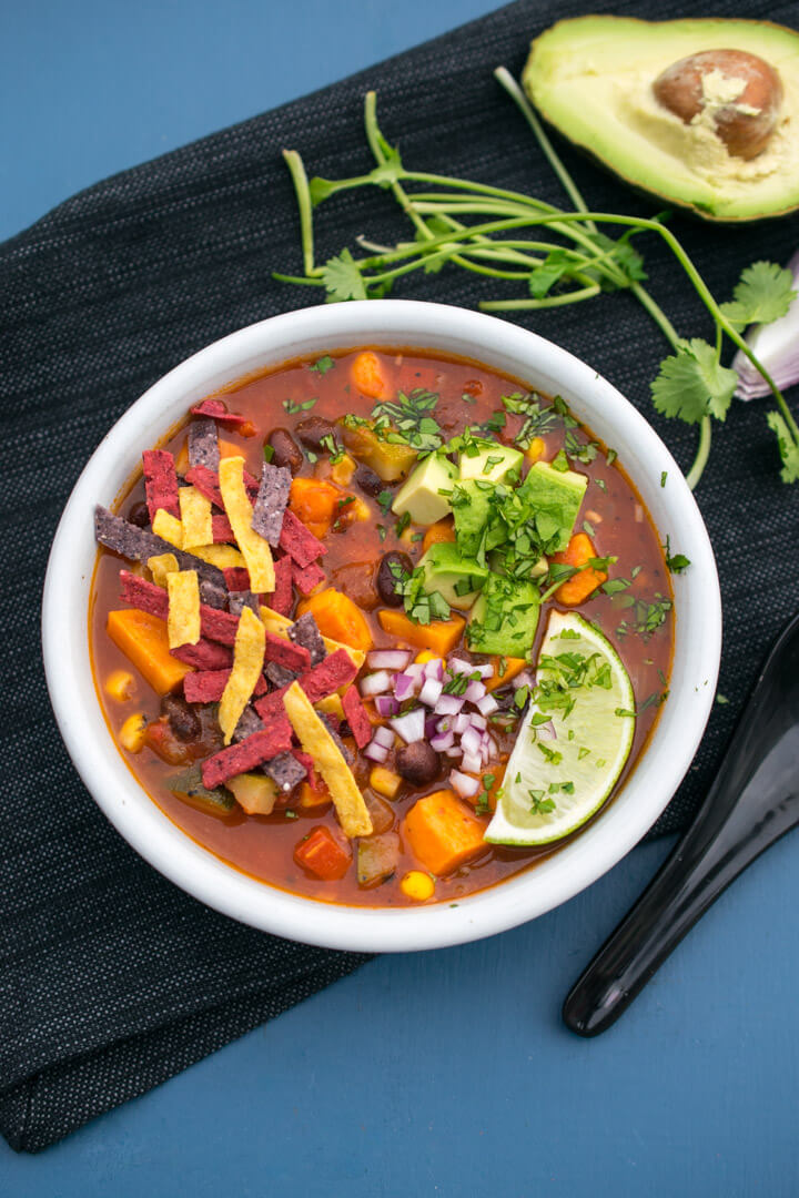 Overhead photo of a bowl of sweet potato tortilla soup with garnishes