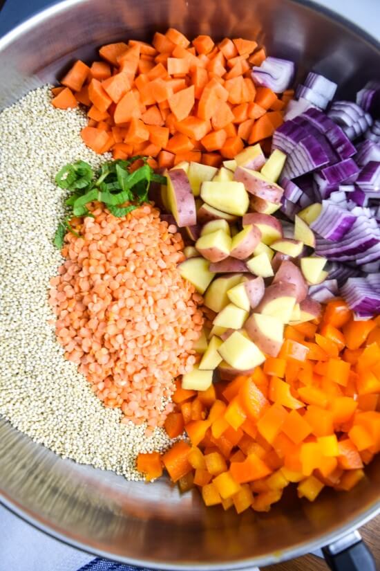 Uncooked photo of a one pot meal in preparation - hearty fresh vegetables and potatoes paired with protein dense red lentils and quinoa for a quick and healthy meal
