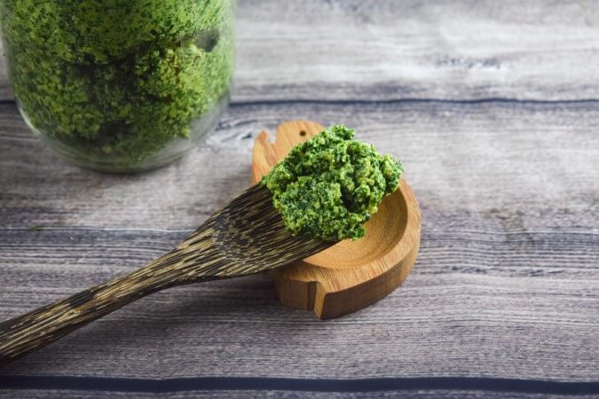 One wooden reusable fork filled with vegan kale, garlic scape, and walnut pesto perfect for a summer pasta!