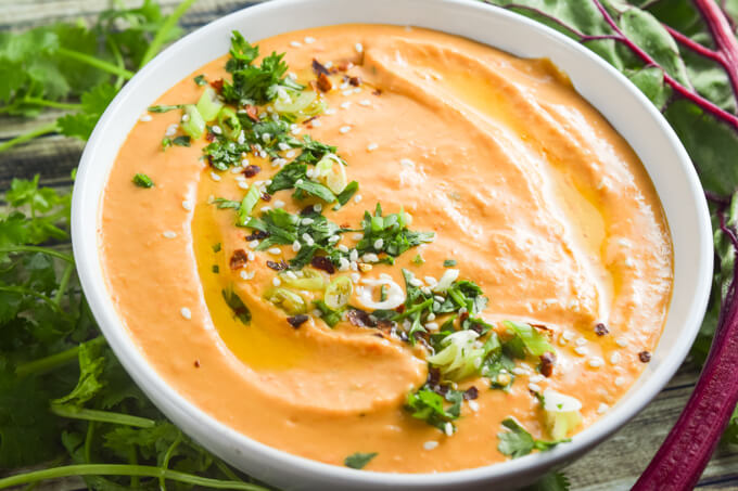 Roasted red pepper white bean hummus spiced with cumin, coriander, red pepper flakes, and bright lemon juice topped with fresh greens and crunchy sesame seeds - makes the perfect appetizer, dip, or spread