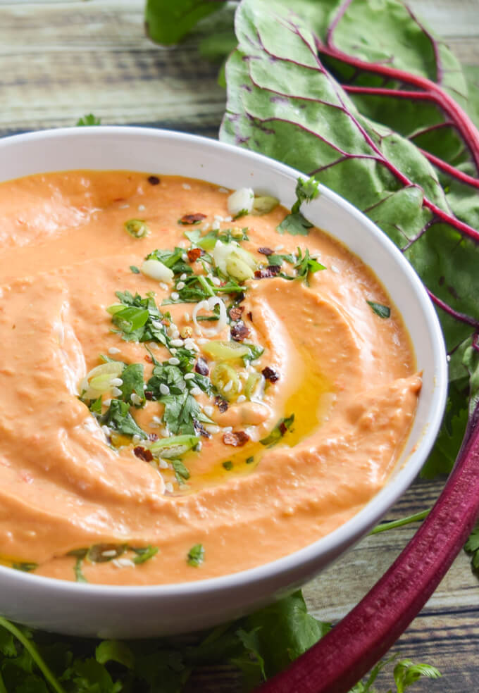 Sweet, smoky, slow roasted red bell peppers, creamy white beans, garlic, and tahini come together to make etherally dreamy and light vegan white bean hummus garnished with cilantro and toasted sesame seeds