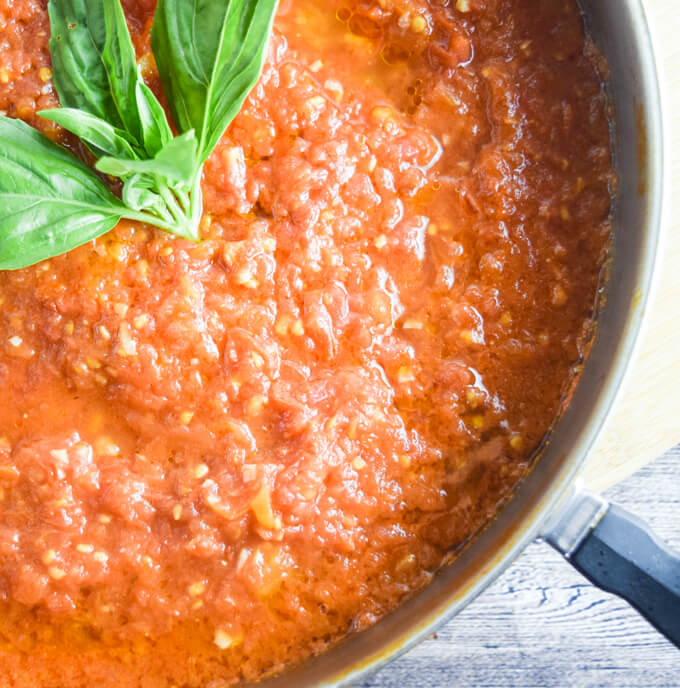 Close up of a pot of fresh and easy tomato marinara garnished with basil