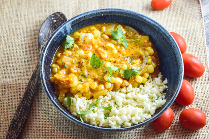 A blue bowl of hearty Indian inspired sweet corn curry spiced with fenugreek, ancho chili powder, garam masala, and turmeric for a flavorful satisfying meal