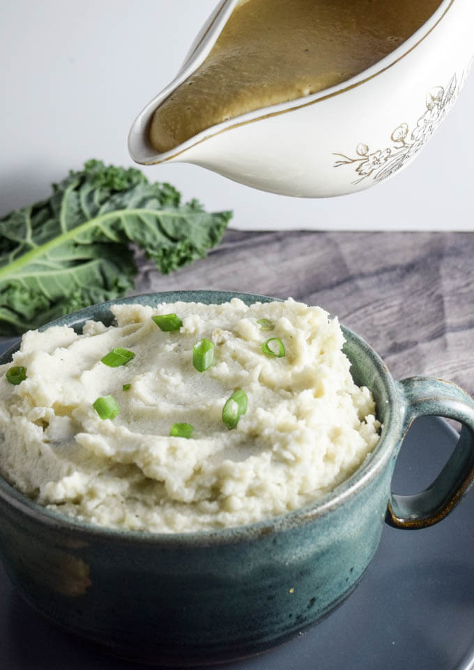 Super creamy and thick vegan gluten, grain, soy, and sugar free garlic roasted mashed potatoes with a hot ladle of healthy white bean gravy