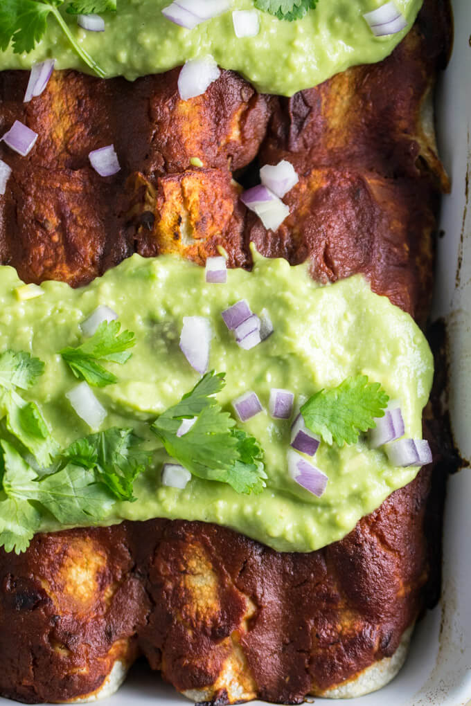 Simple baked enchilada breakfast tray filled with hearty blended beans, vegetables, cumin, and coriander. Spicy and filling! Soaked in a tomato based, garlic, oregano, and paprika sauce and topped with a delicious avocado puree
