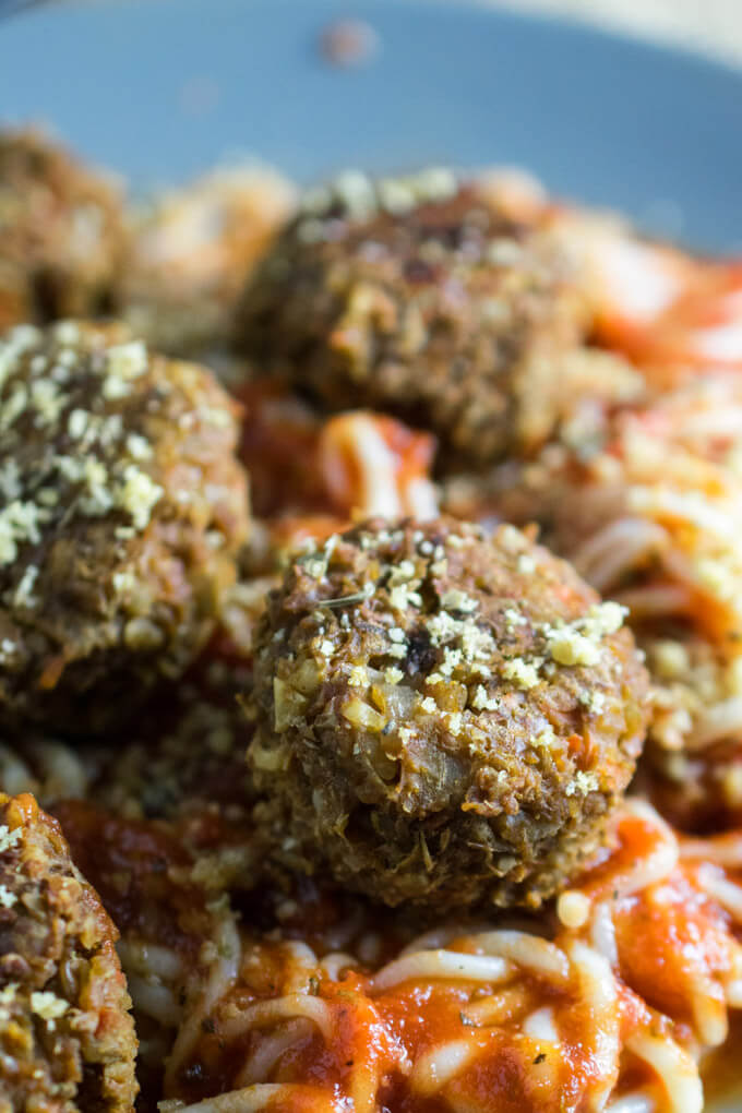 Closeup of nutritional powerhouse vegan meatballs made with green lentils, walnuts, nutritional yeast, and carrots and served with light shiritaki noodles and tomato sauce