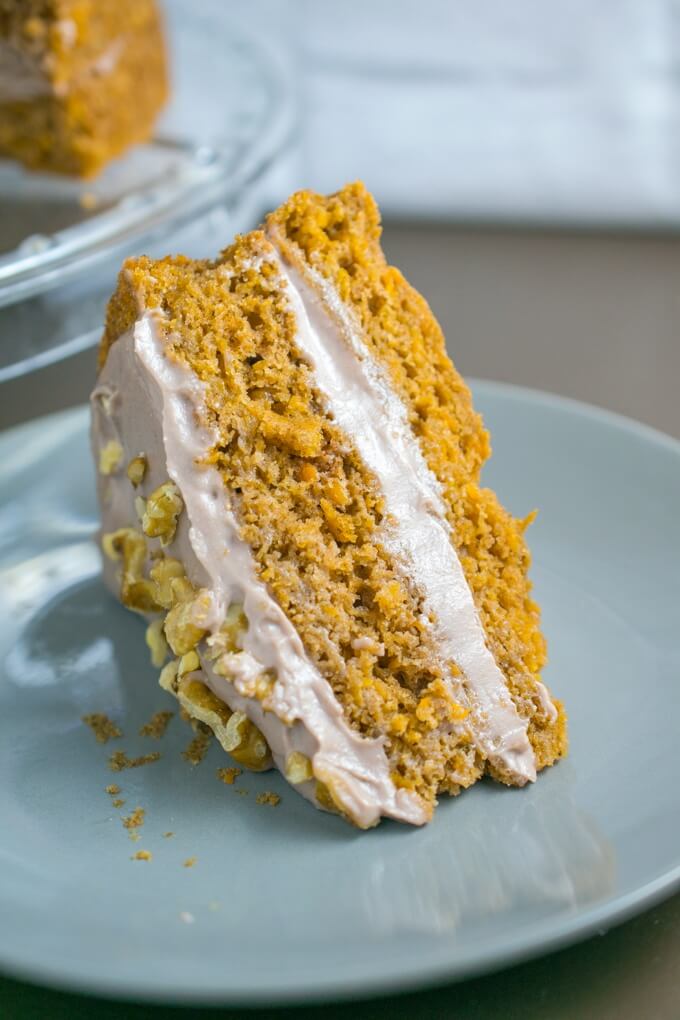Closeup of one slice of vegan sweet potato carrot cake with a dense crumb, chewy shredded sweet potato, and a gooey toasted walnut cinnamon icing sandwiched between two layers