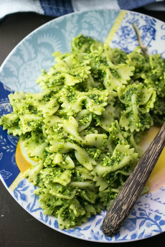 A serving of vegan edamame pesto pasta on a blue patterned plate with a wooden fork