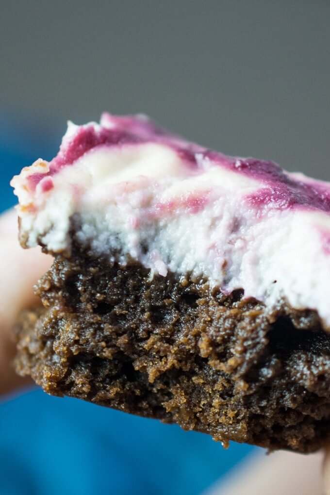 Extreme close-up of the moist center of a fudgy vegan cheesecake brownie with creamy cheesecake and cherry swirl topping.