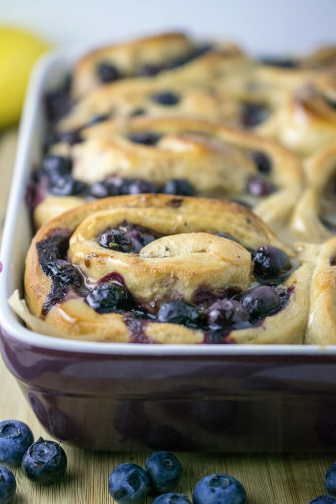 Vegan Blueberry Sweet Rolls in their baking dish after adding orange caramel glaze. Topped with more fresh blueberries.