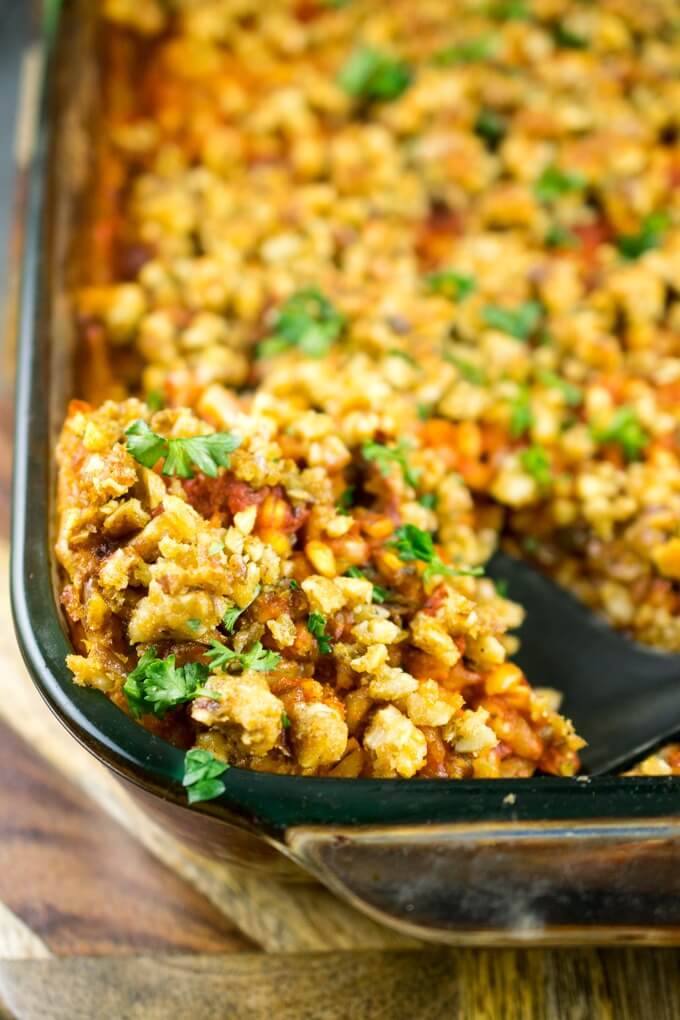 Close-up of a serving of walnut herb baked farro being scooped out of the baking dish with a slotted spoon