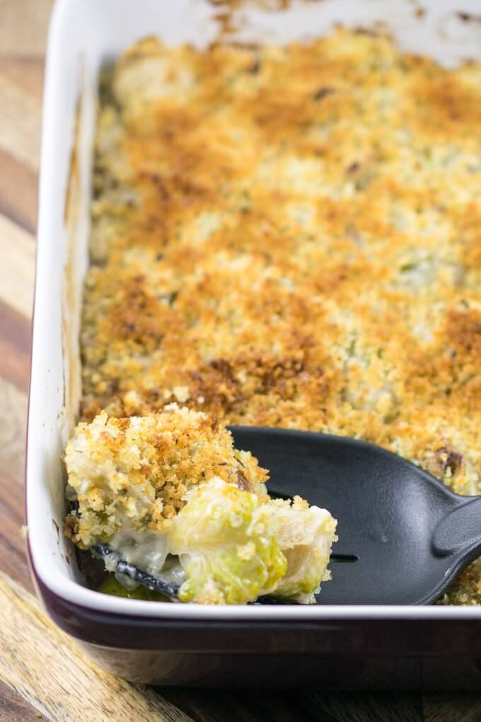 A breadcrumb-topped vegan Brussels sprout casserole with a spoon scooping out a portion
