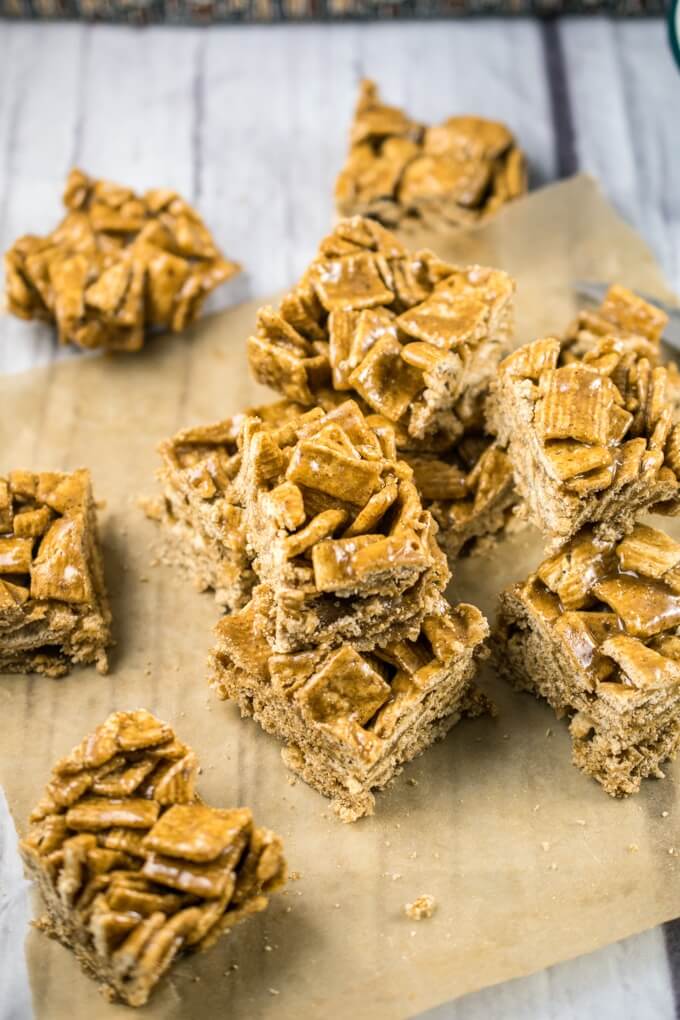 Cinnamon toast cereal clusters cut into squares and arranged on a piece of parchment paper atop a wooden table