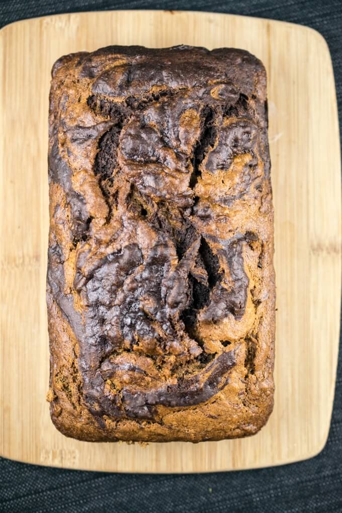 Overhead view of vegan chocolate banana bread on a wooden cutting board, showing the chocolate swirl pattern on the surface
