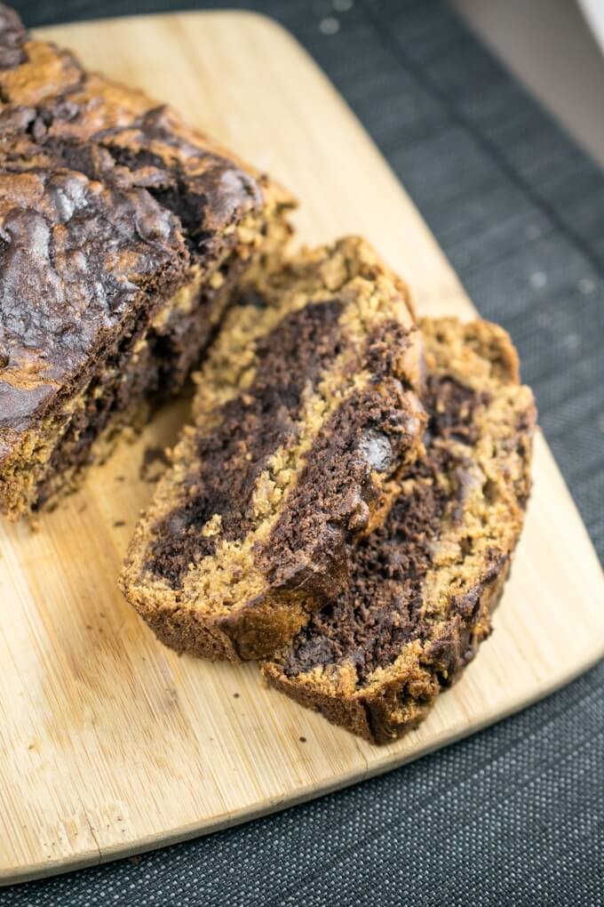 Two slices of vegan chocolate swirl banana bread showing the swirled light brown and chocolate brown pattern and melted chocolate chips in the interior
