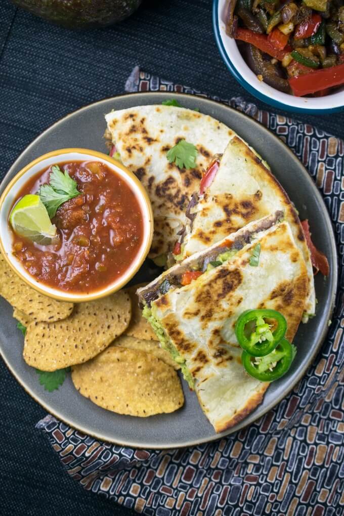 Overhead view of dairy-free quesadillas arranged on a plate surrounding a bowl of red salsa topped with cilantro.