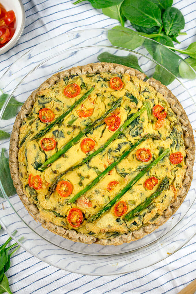 Overhead view of a vegan quiche in a pie dish with a brown spelt pie crust.