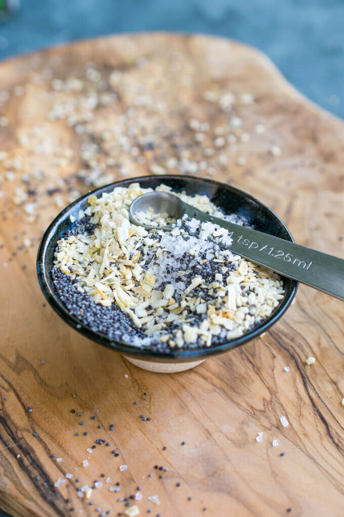 Everything bagel seasoning mixed together in a small dish with a teaspoon measuring spoon.