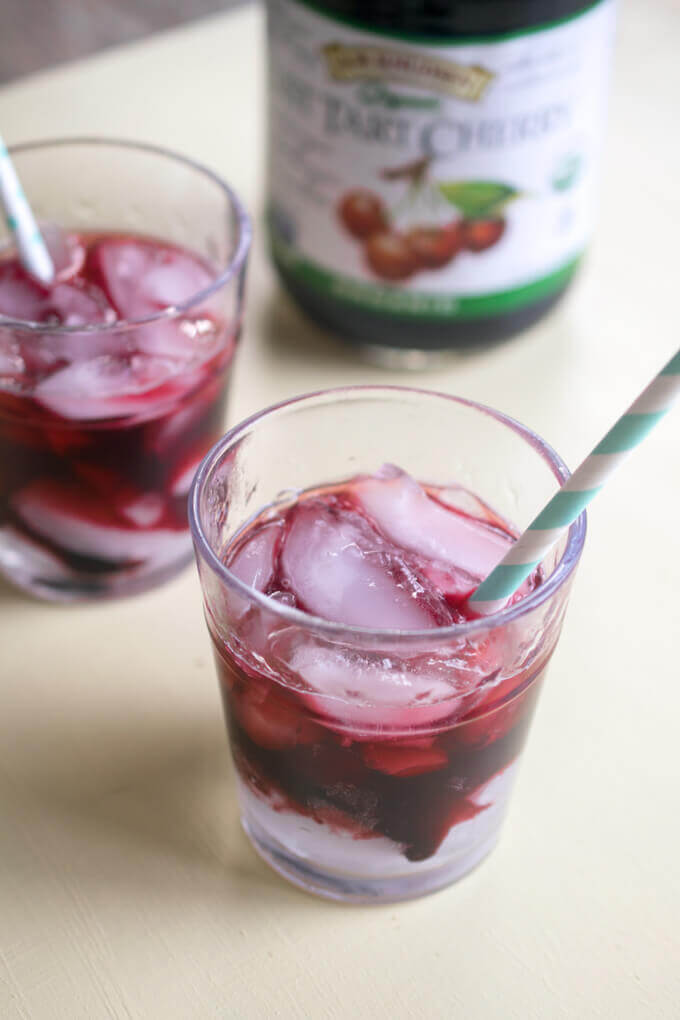 Tart cherry coolers in clear glasses with ice cubes and blue striped straws