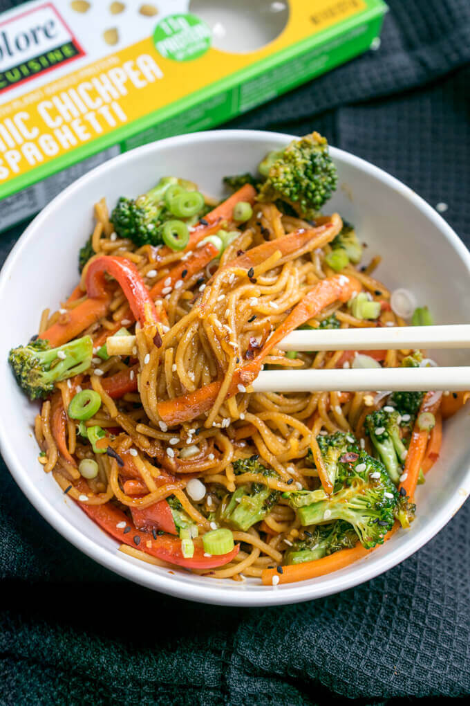 Vegan garlic sesame noodles with chopsticks and pieces of broccoli and pepper visible.