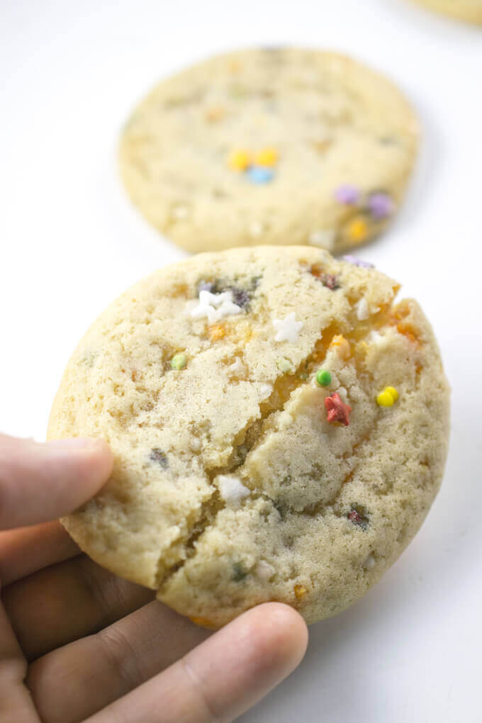 A vegan sugar cookie being bent in half to demonstrate its soft and chewy texture