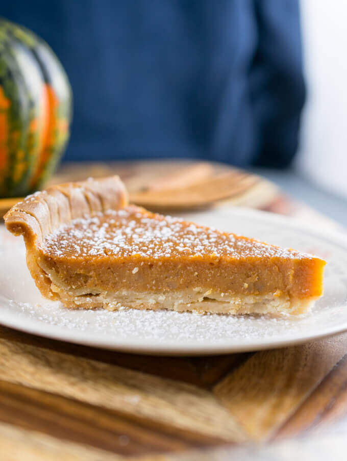 Side view of a slice of vegan sweet potato pie, showing flaky layers of crust and a clean slice