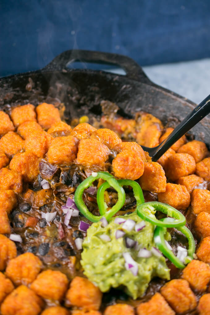 A portion of sweet potato hotdish being served with red onion and guacamole