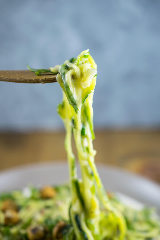 Close-up of a forkful of vegan garlic zucchini noodles showing the noodles coated with creamy sauce