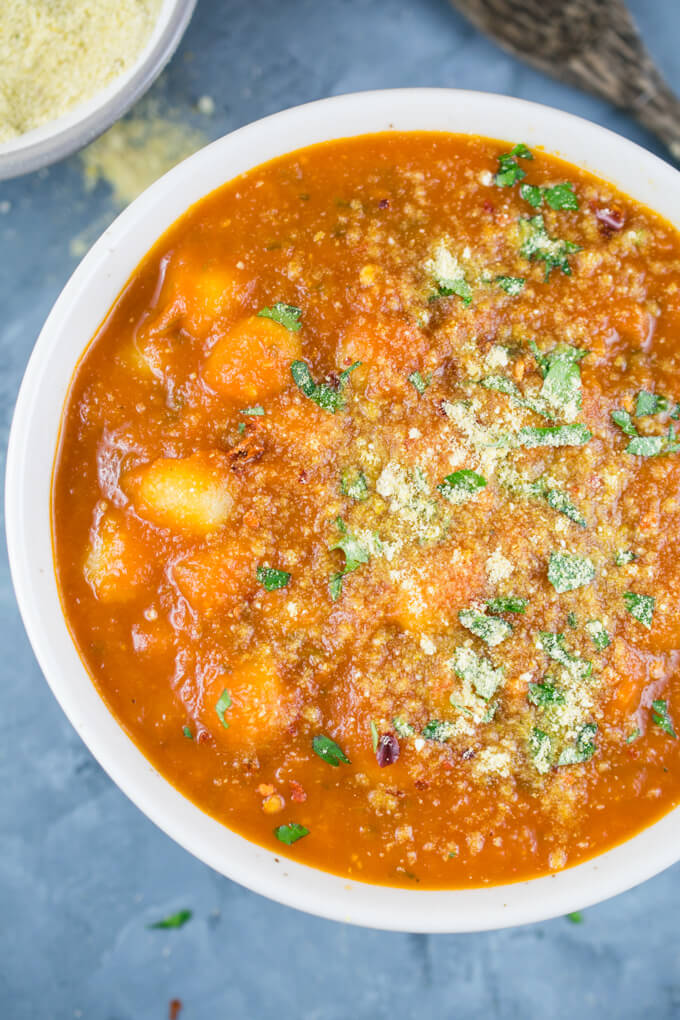 Close-up of a bowl of tomato basil gnocchi soup, where the creamy tomato texture and individual gnocchi can be seen