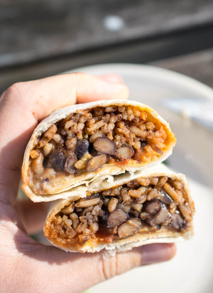 Photograph of a vegan burrito after being microwaved and then sliced in half, showing the rice and beans on the interior