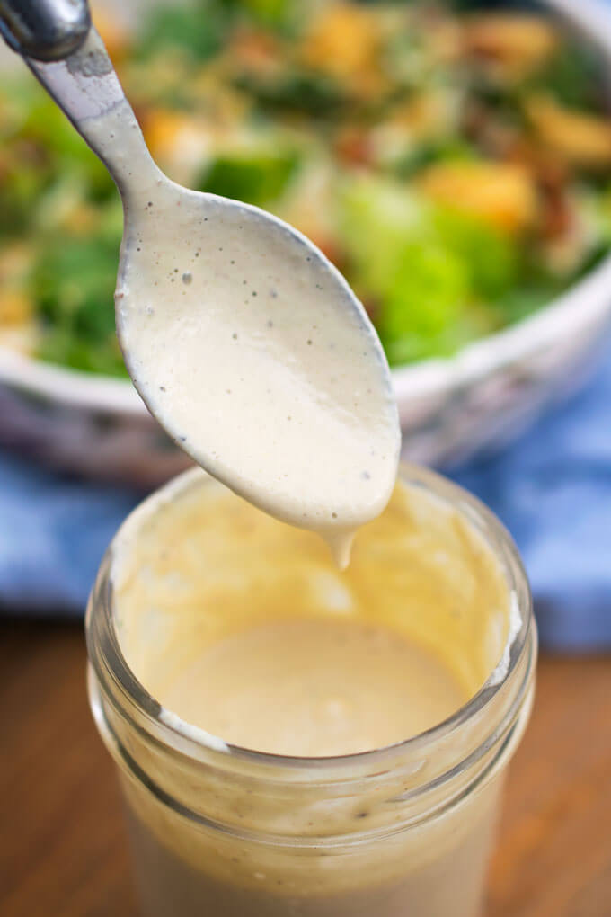 A spoonful of smooth and creamy vegan caesar dressing being spooned into a jar.