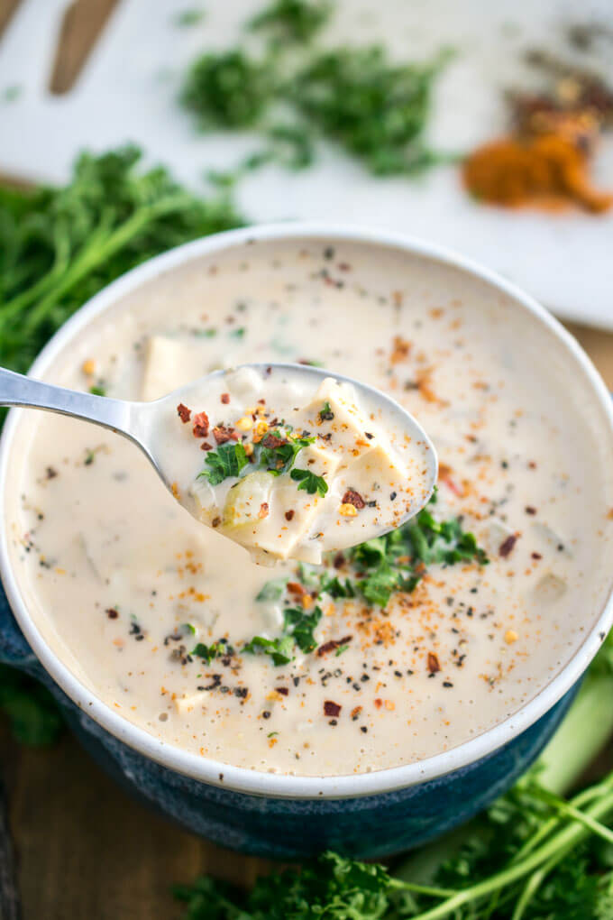 A spoonful of vegan clam chowder showing chunks of potato and yuba