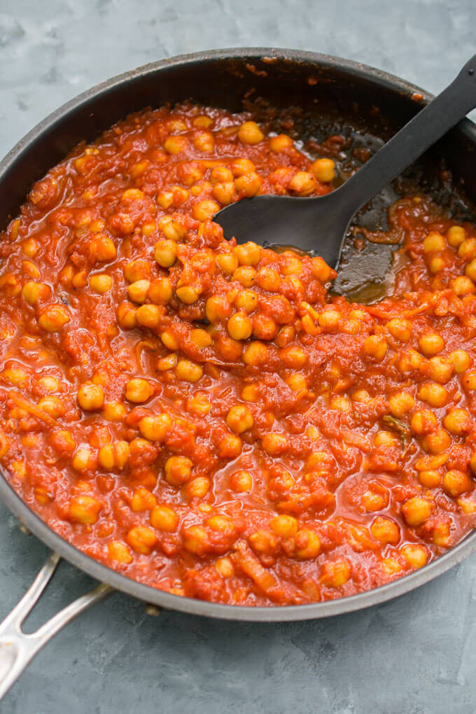 Chickpeas fra diavolo in a skillet, showing the bright red color and glistening, thick texture of the sauce.