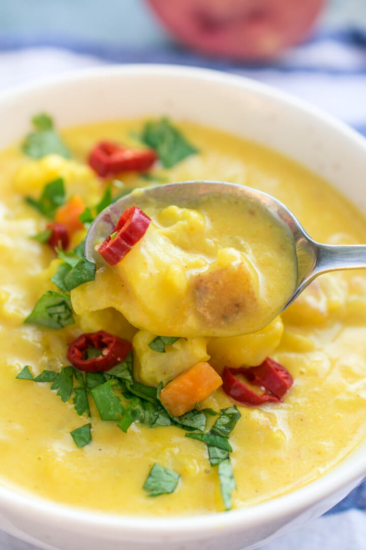 A spoonful of curried cauliflower chowder showing the rich, creamy texture and pieces of carrot and potato